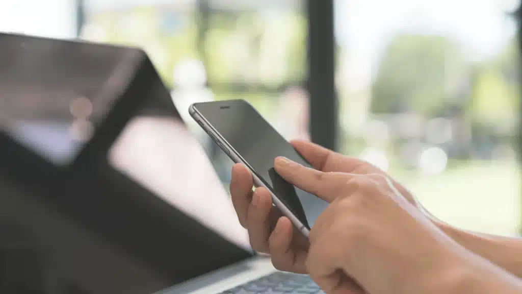 Persona utilizando un teléfono móvil para gestionar procesos de cobranza telefónica, en contexto de cambios regulatorios asociados a la normativa de prefijos.